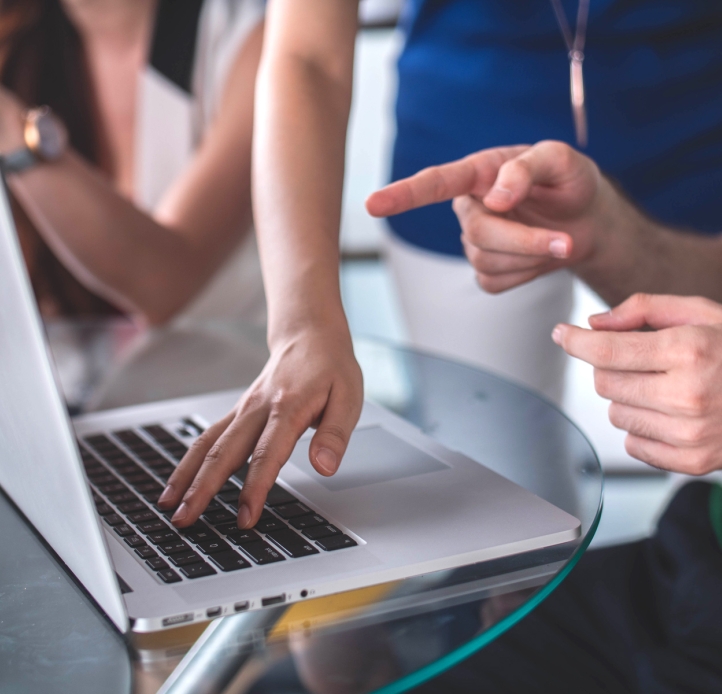 Hands pointing to a laptop on a table