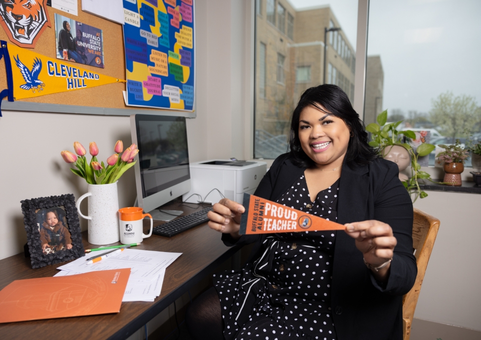 Brianna Ware at desk with Buffalo State alumni banner